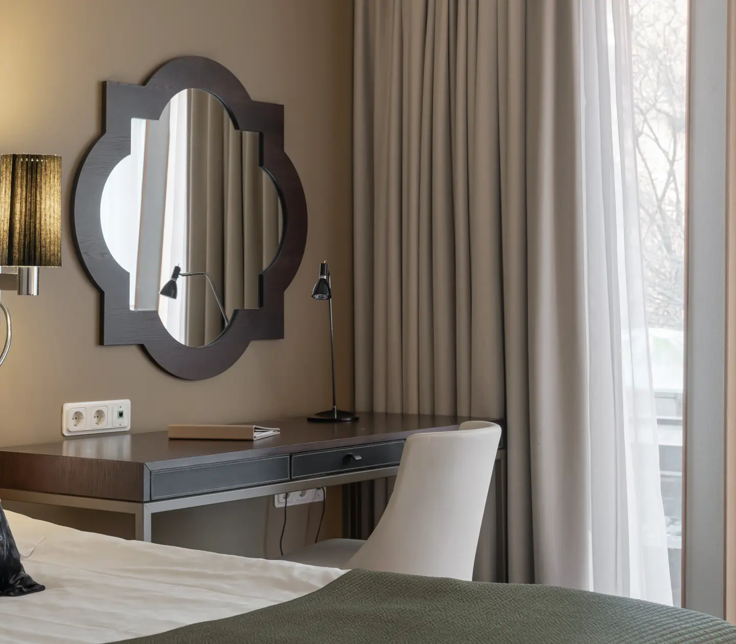 Mysigt hotellrum med säng, spegel och skrivbord