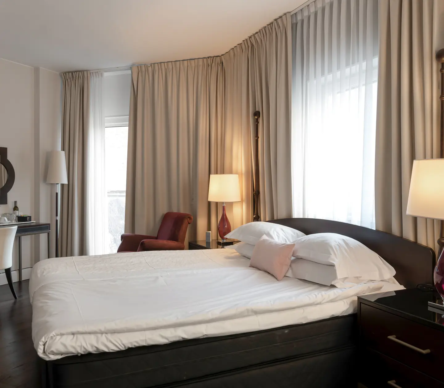 Mysigt hotellrum med säng, gardiner och skrivbord