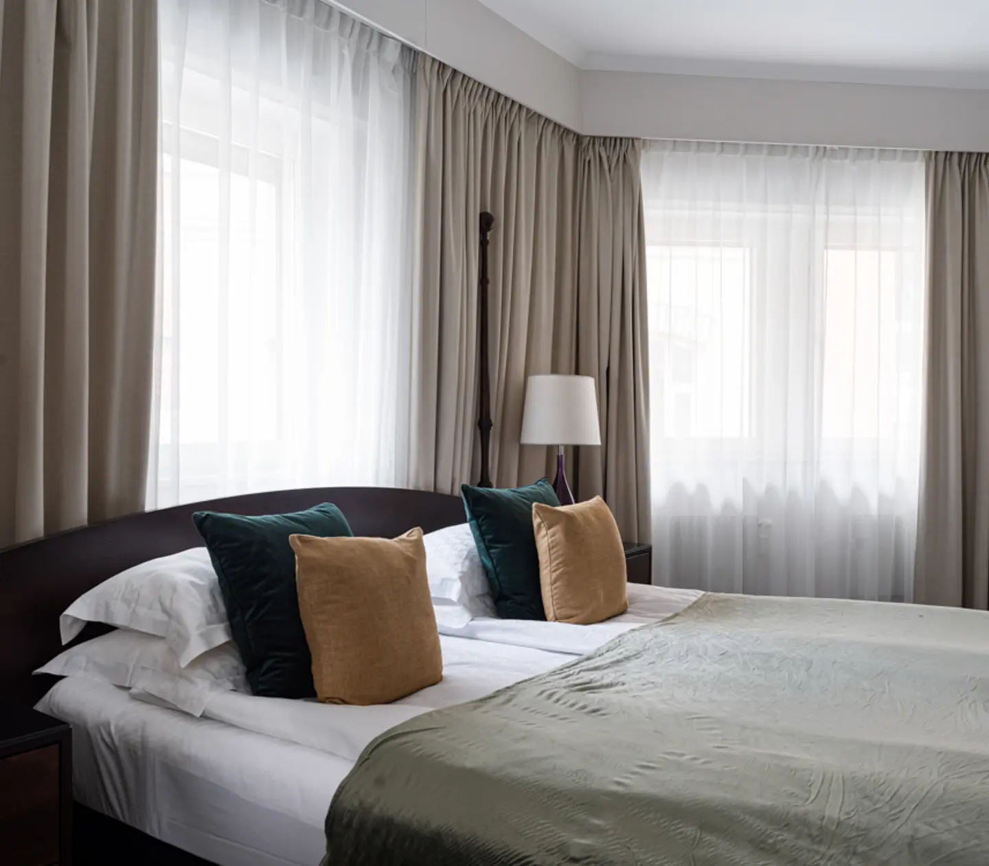 Ljust hotellrum med säng, skrivbord och sänglampa