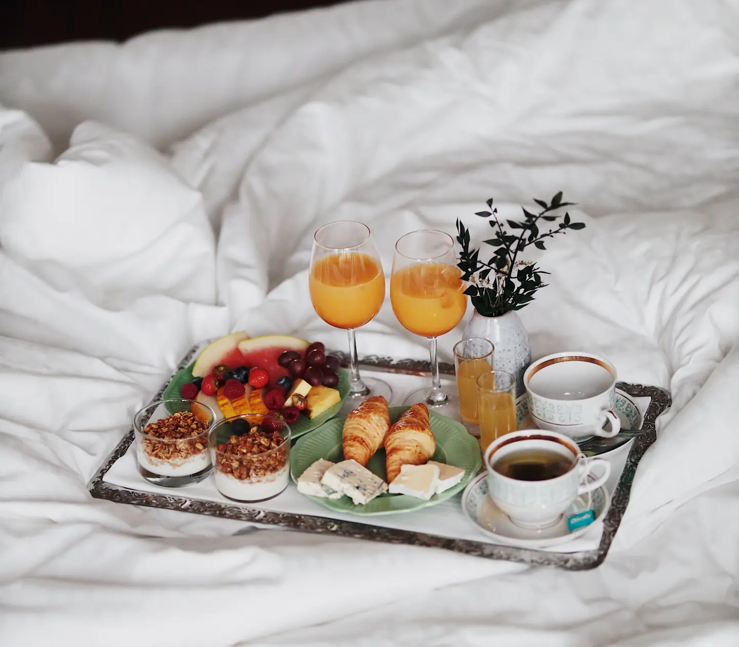 Frukostbricka med kaffe, frukt och juice på hotellsäng