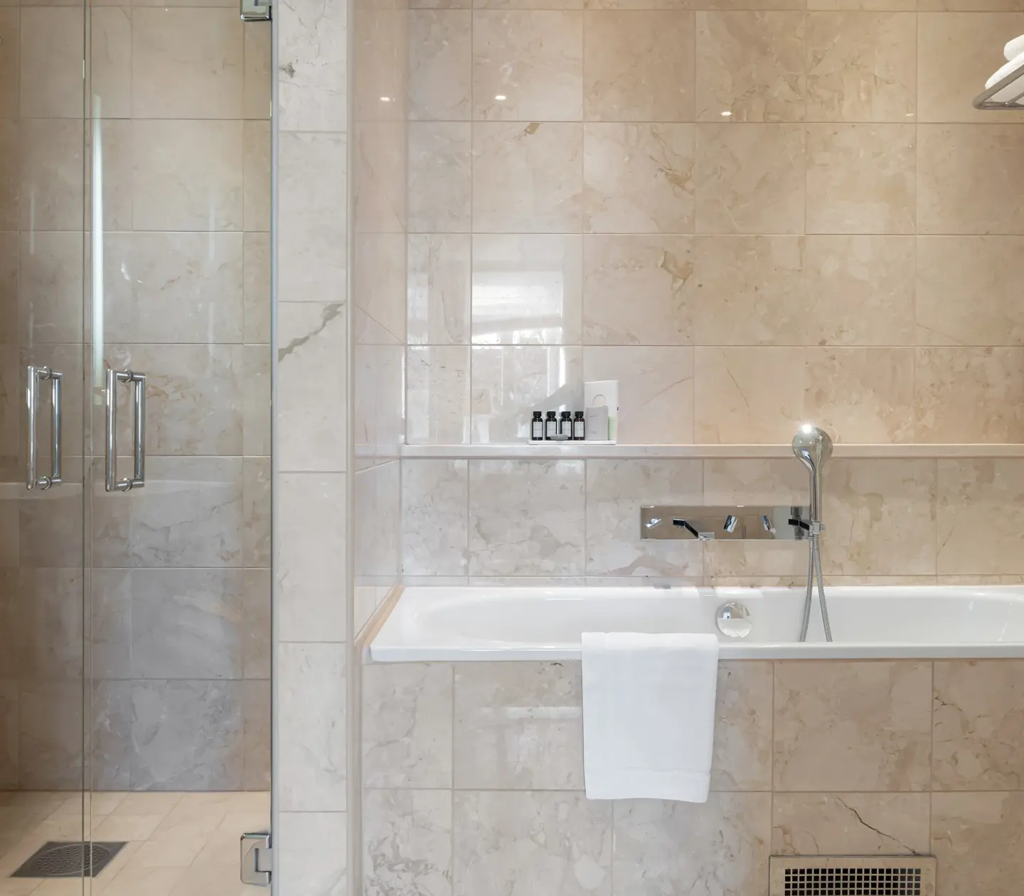Beige badrum med dusch, badkar och handdukar