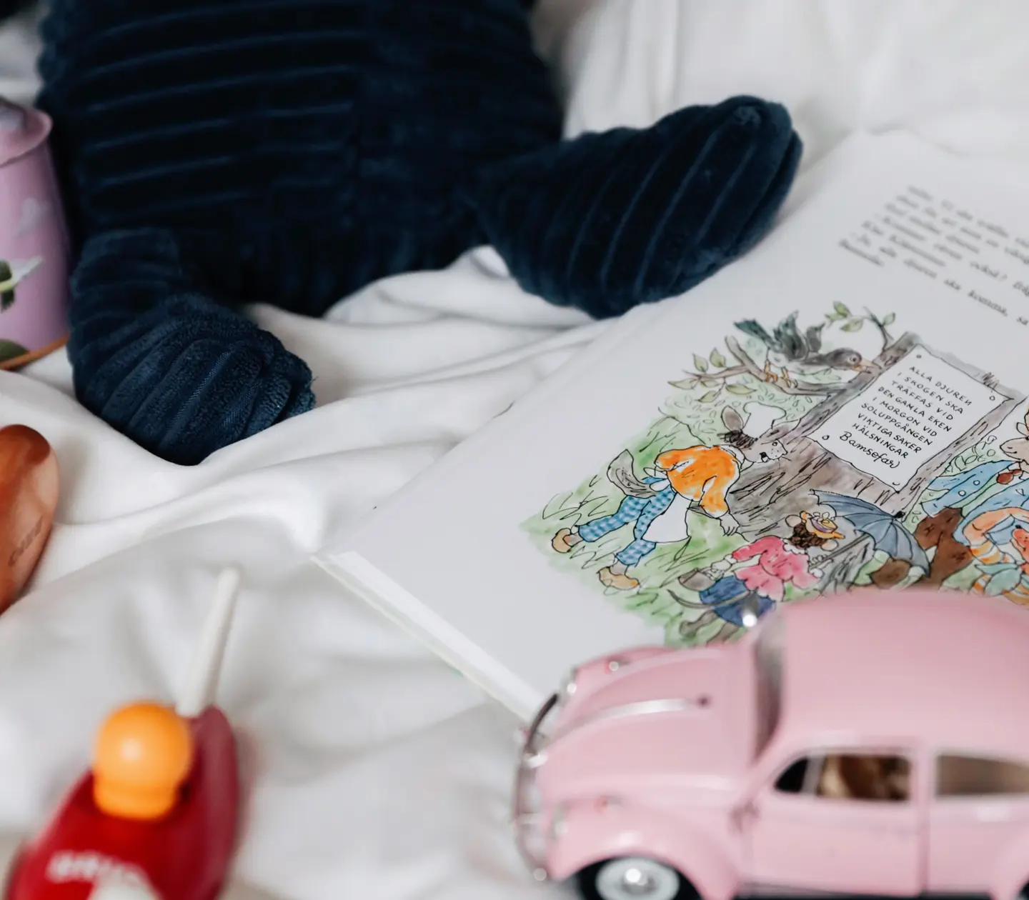 Barnbok, leksaksbil och del av nalle