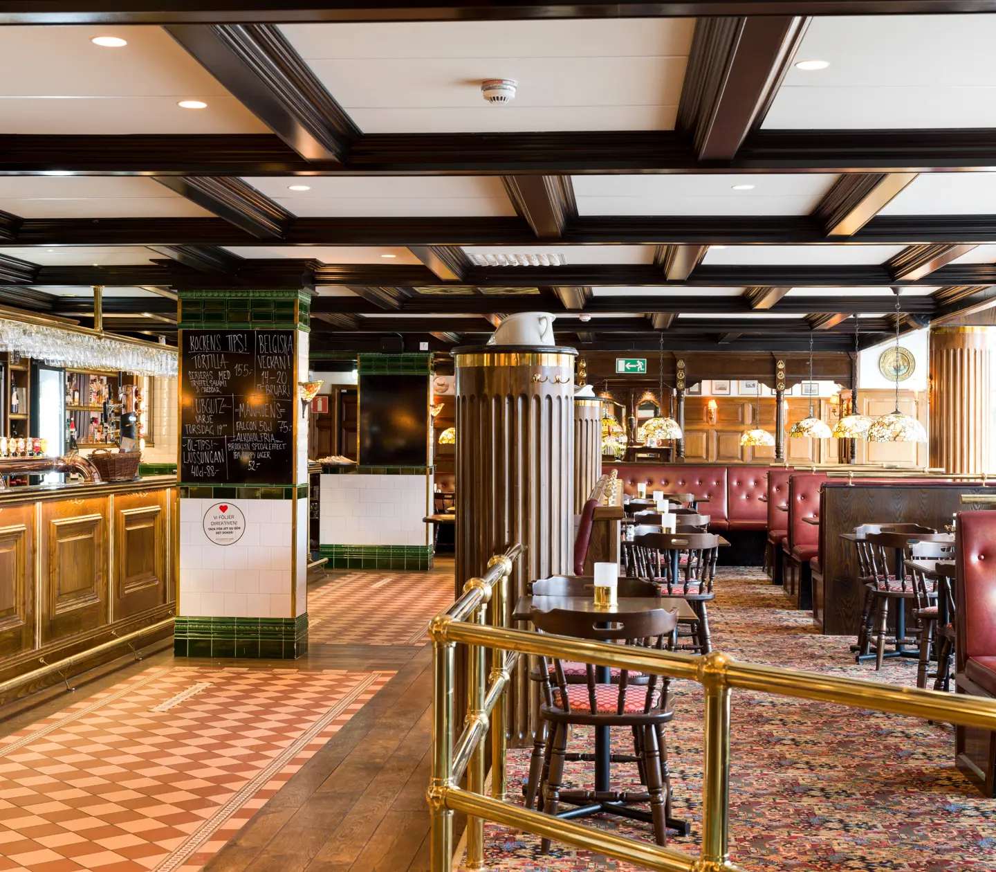 Pubmiljö med sittplatser, bar och menyer på svarta tavlor