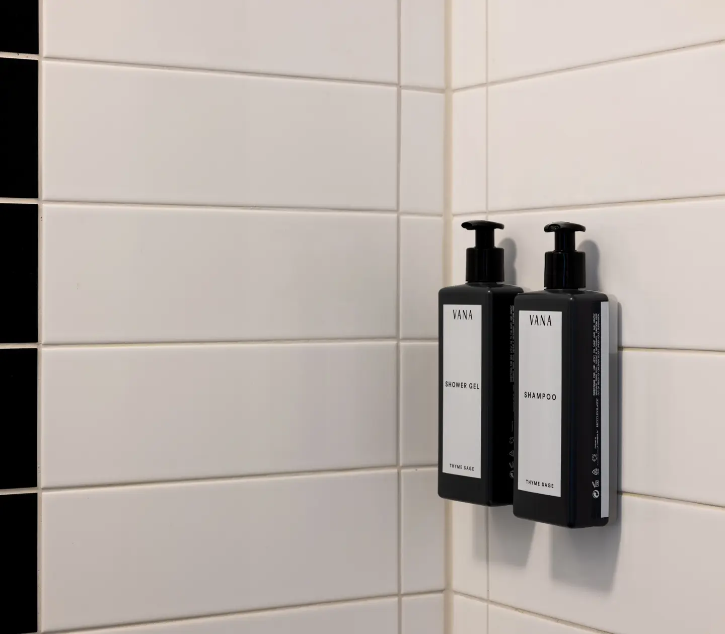 Badrum med svart och vitt kakel och närbild på Shampoo och Shower Gel från Vana