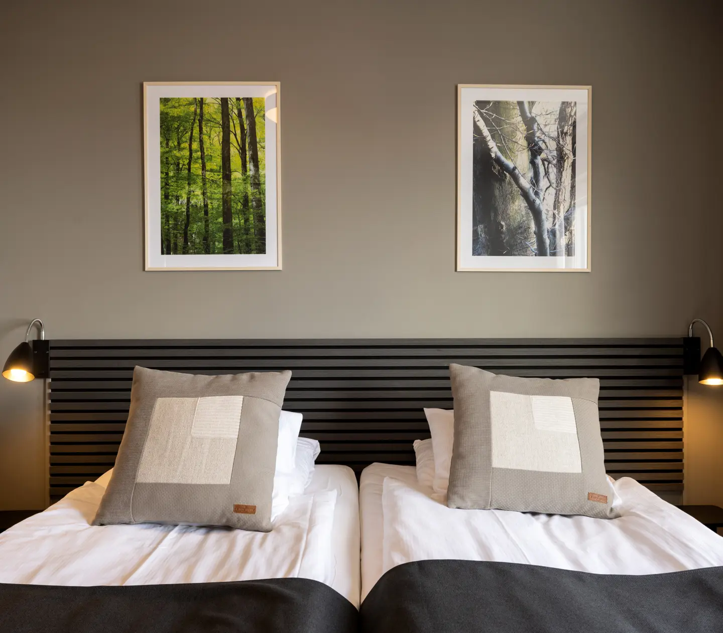 Hotellrum med sängar, svart sänggavel och tavlor