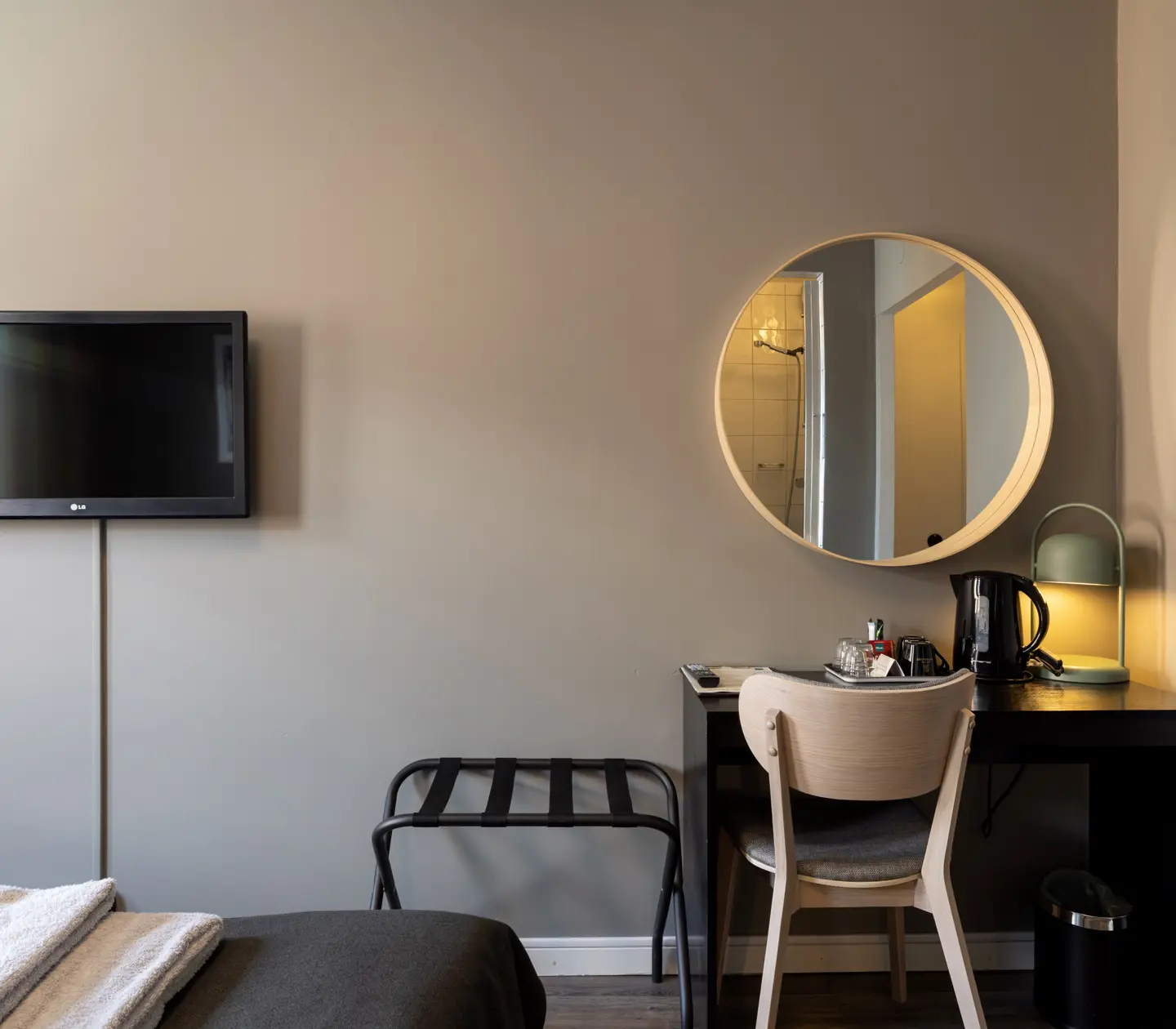 Hotellrum med skrivbord, rund spegel och tv