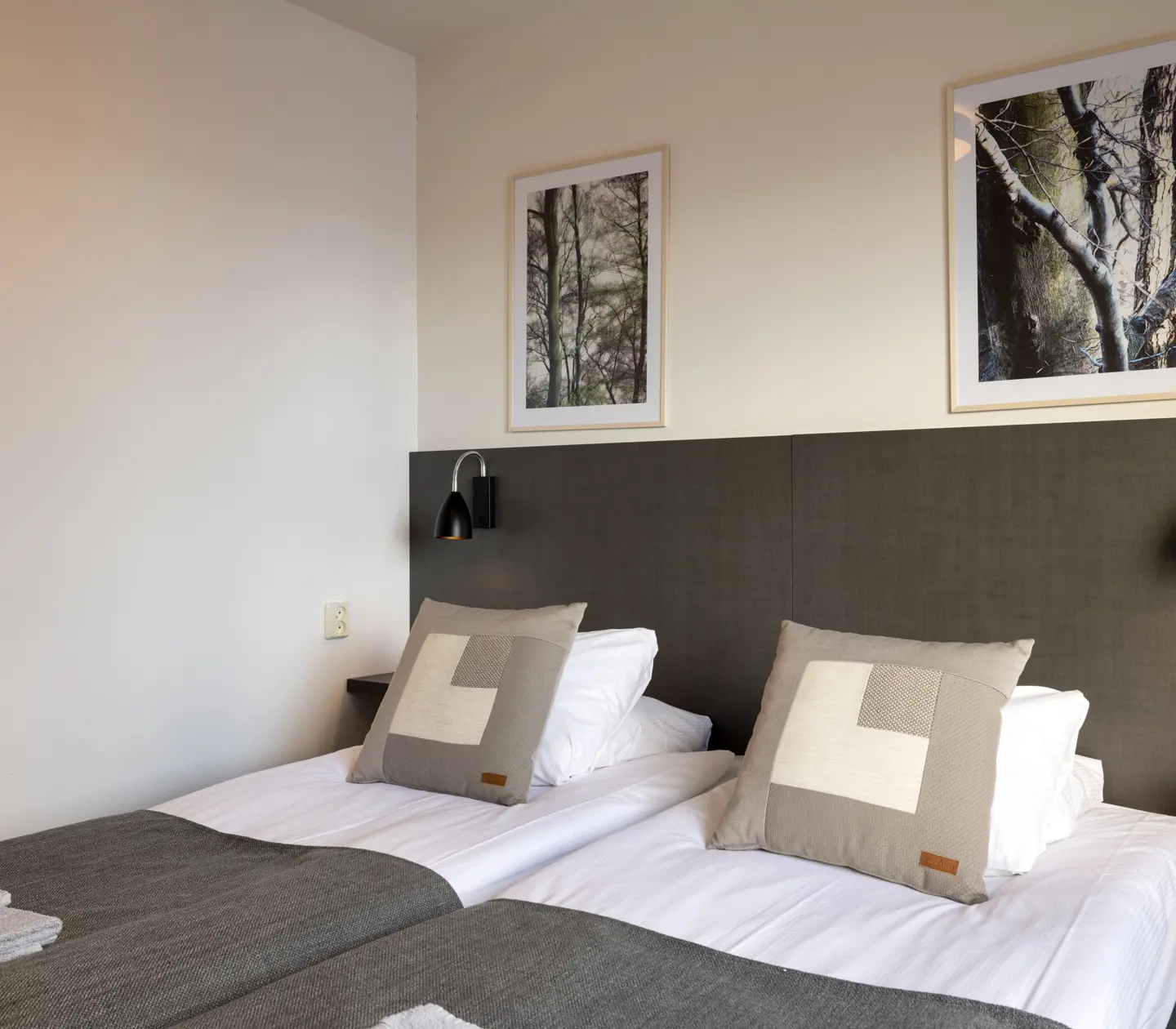 Hotellrum med sängar, svart sänggavel och tavlor