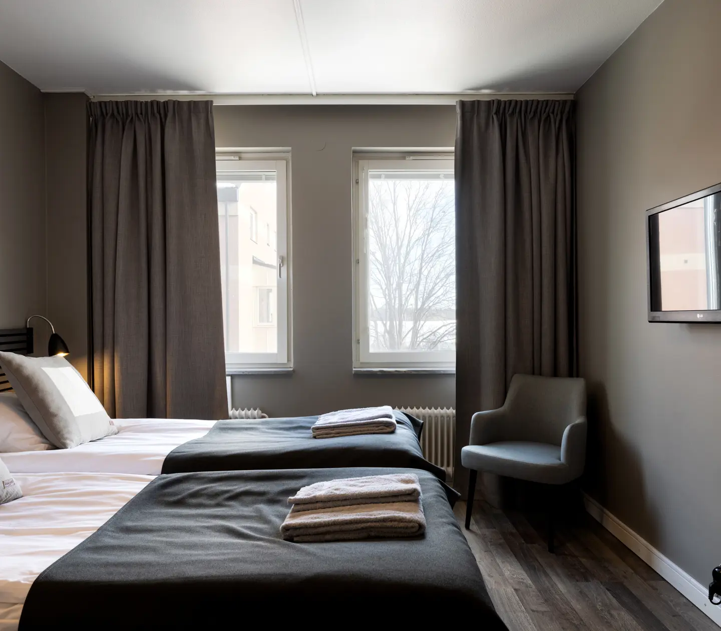Hotellrum med sängar, svart sänggavel och fåtölj