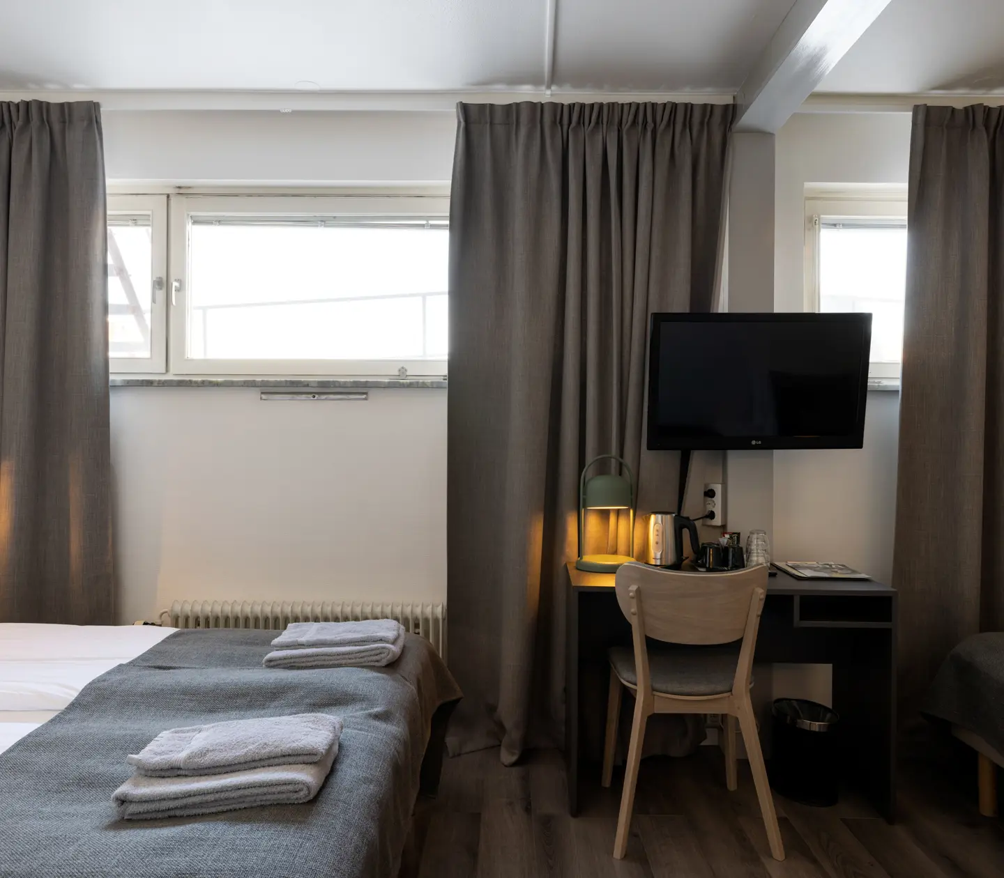 Hotellrum med tre sängar, skrivbord och tv