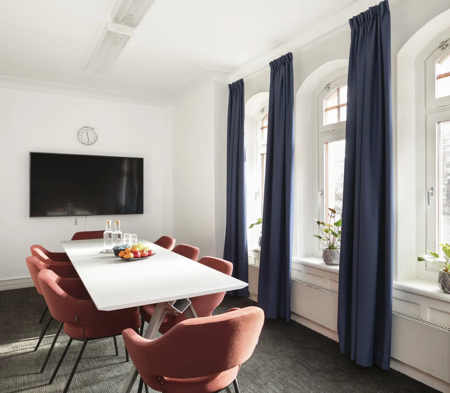 Konferensrum med röda stolar, tv och fönster