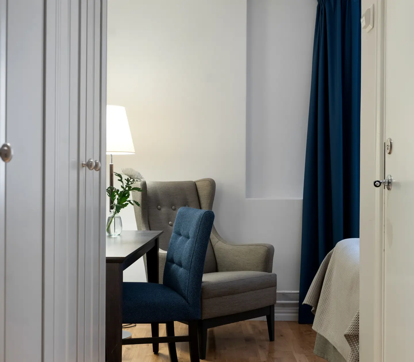 Ljust hotellrum med fåtölj, skrivbord och garderob