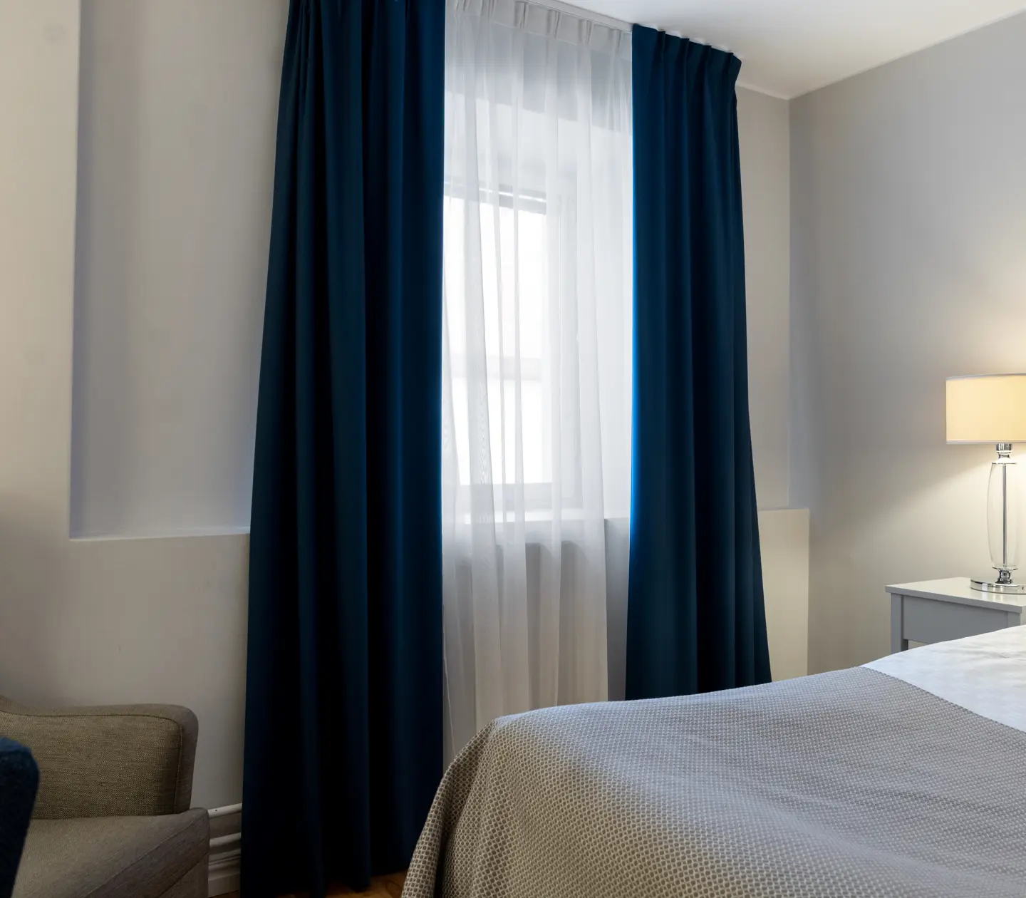 Ljust hotellrum med säng, fönster och gardiner