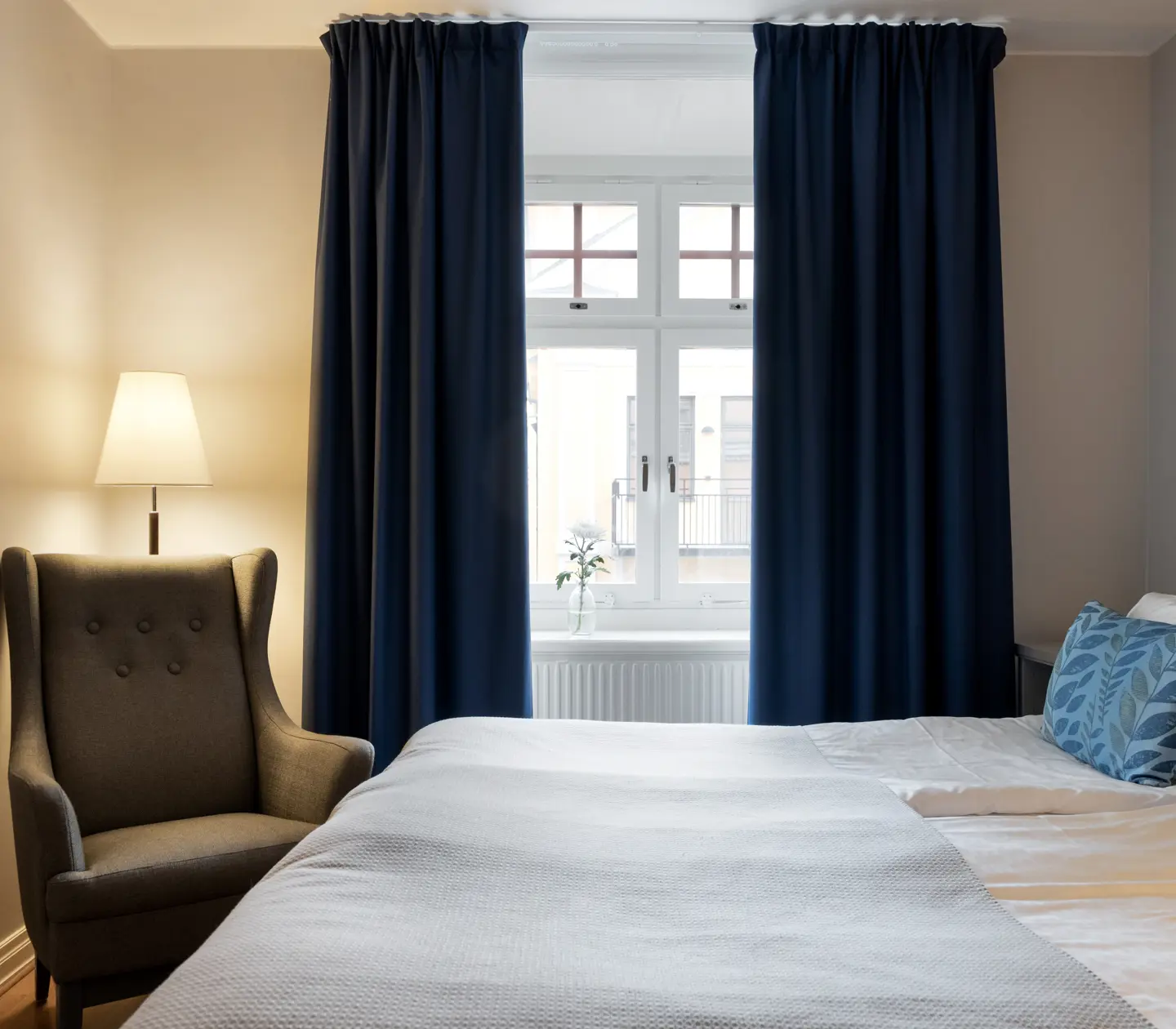 Ljust hotellrum med säng, fåtölj och fönster