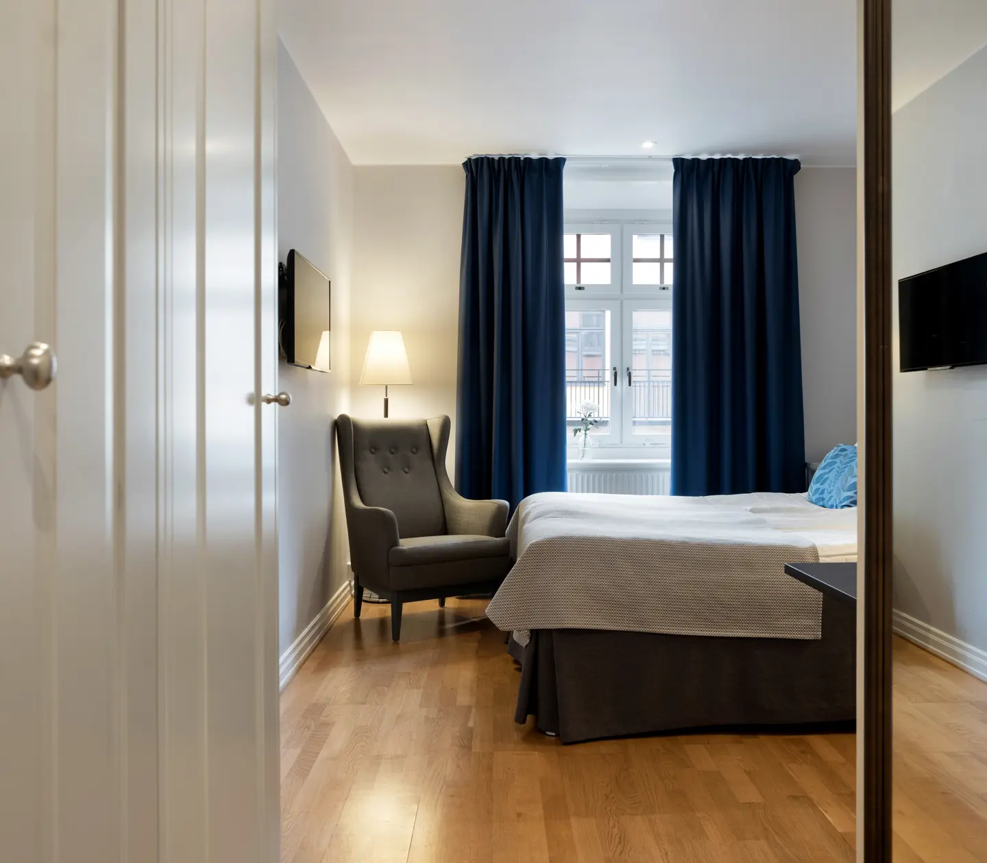 Ljust hotellrum med säng, fåtölj och fönster