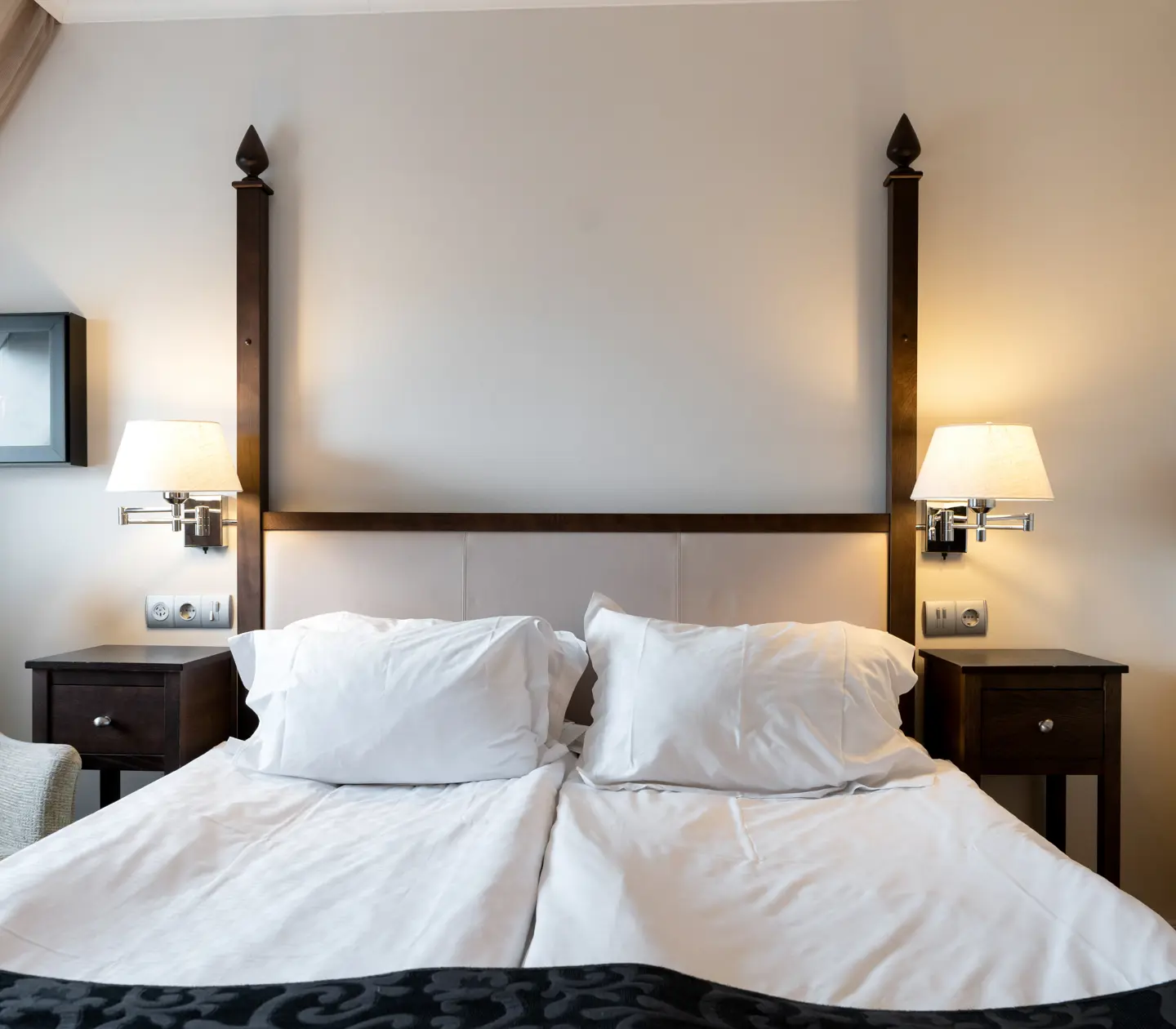 Ljust hotellrum med säng, tavla och fåtölj