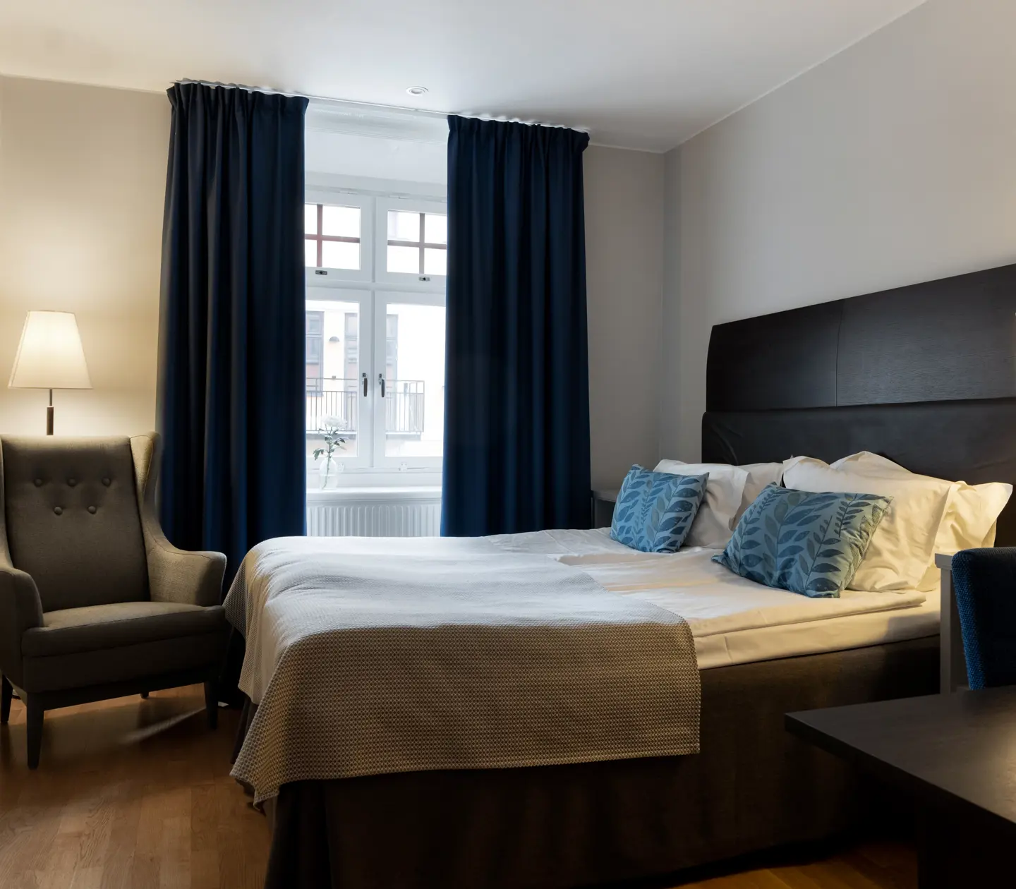 Ljust hotellrum med säng, fåtölj och fönster