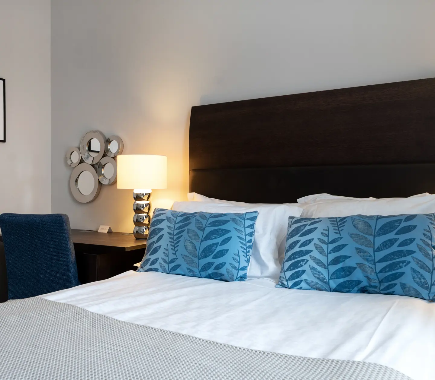 Ljust hotellrum med säng, skrivbord och tavla