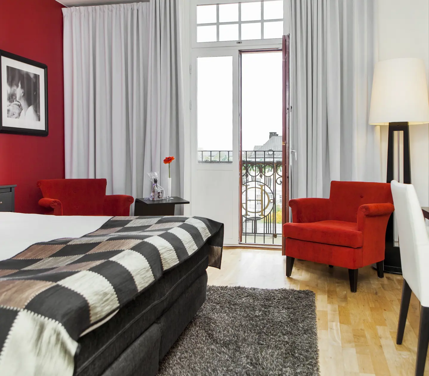 Hotellrum med röd vägg, säng och röda fåtöljer