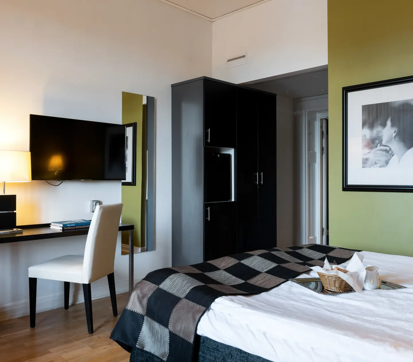 Hotellrum med grön vägg, säng och skrivbord