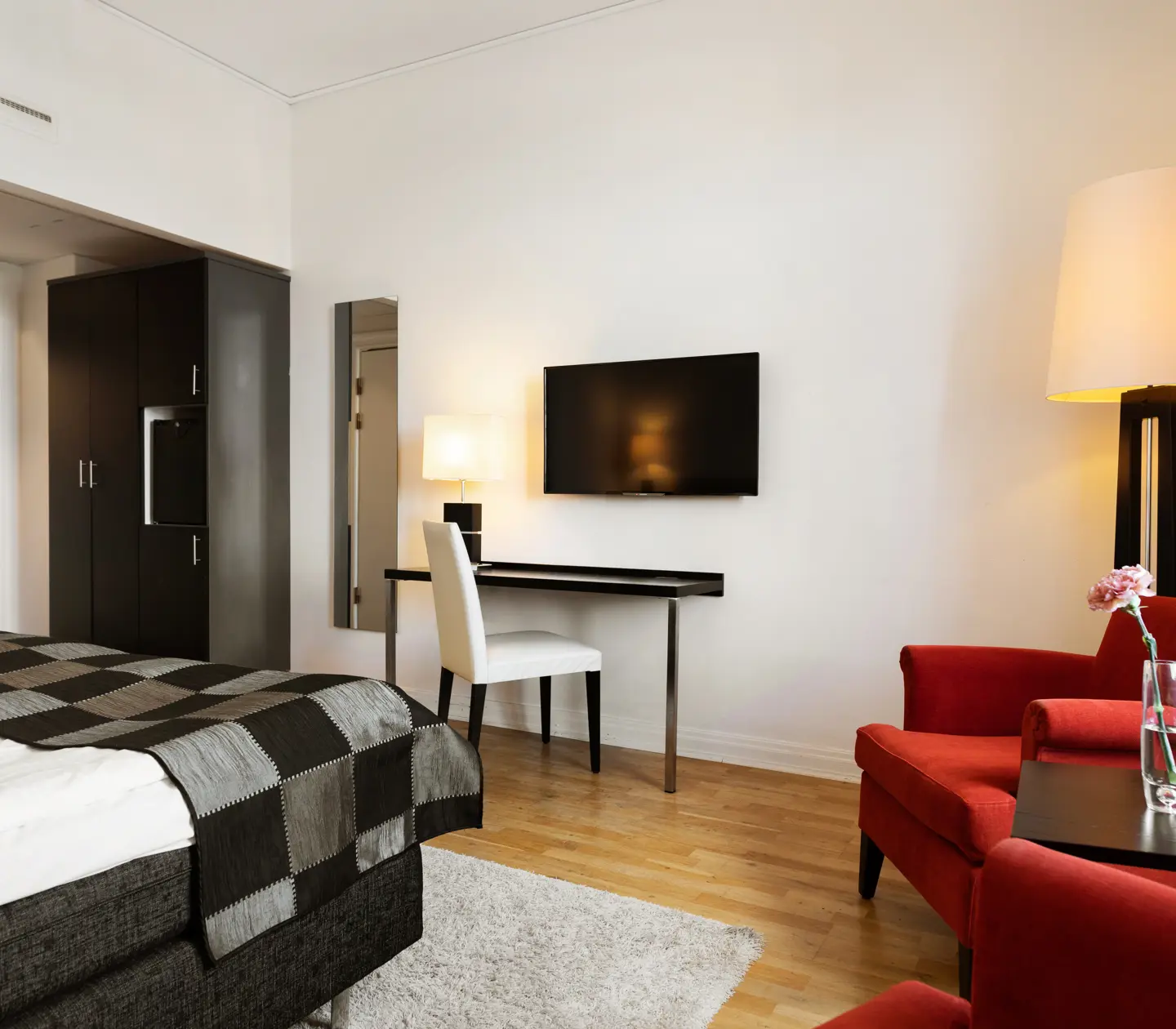 Hotellrum med röda fåtöljer, skrivbord och garderob