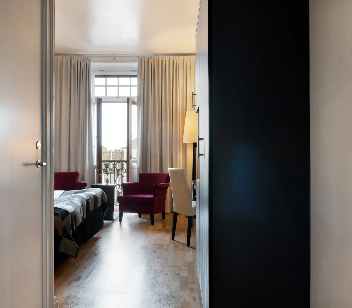 Hotellrum fåtöljer, dörr ut till balkong och garderob