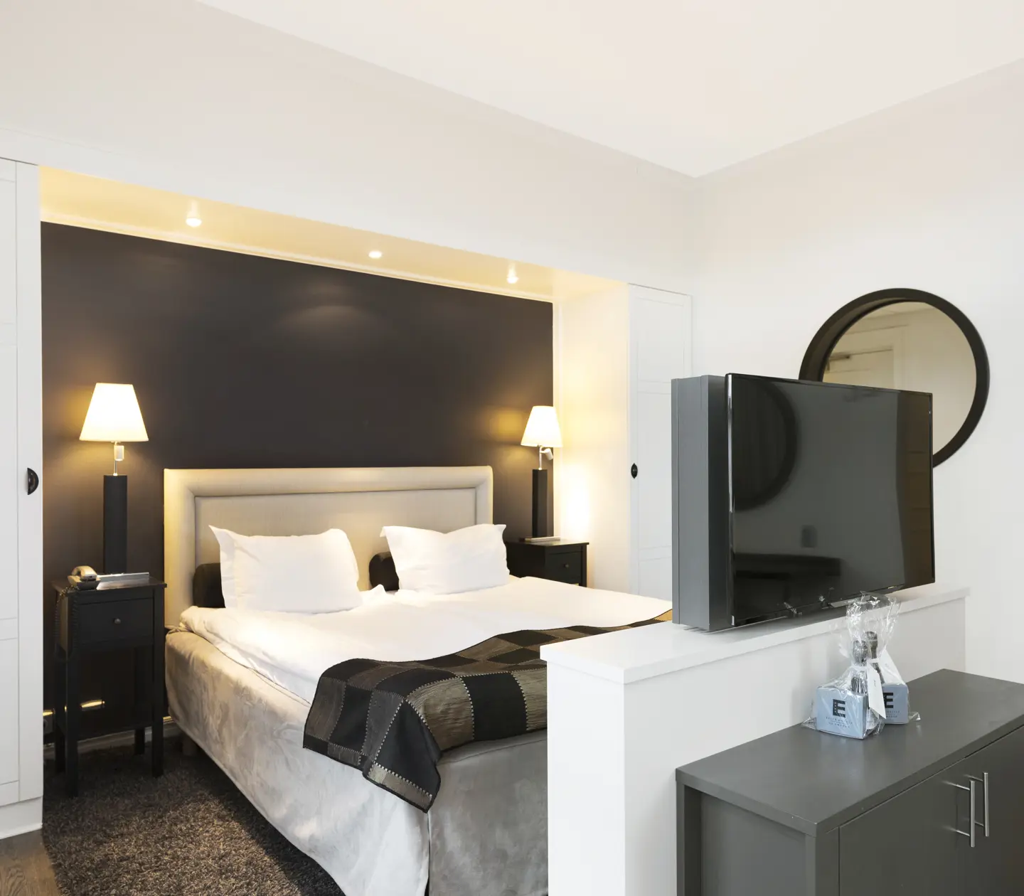 Ljust hotellrum med säng, tv och garderob