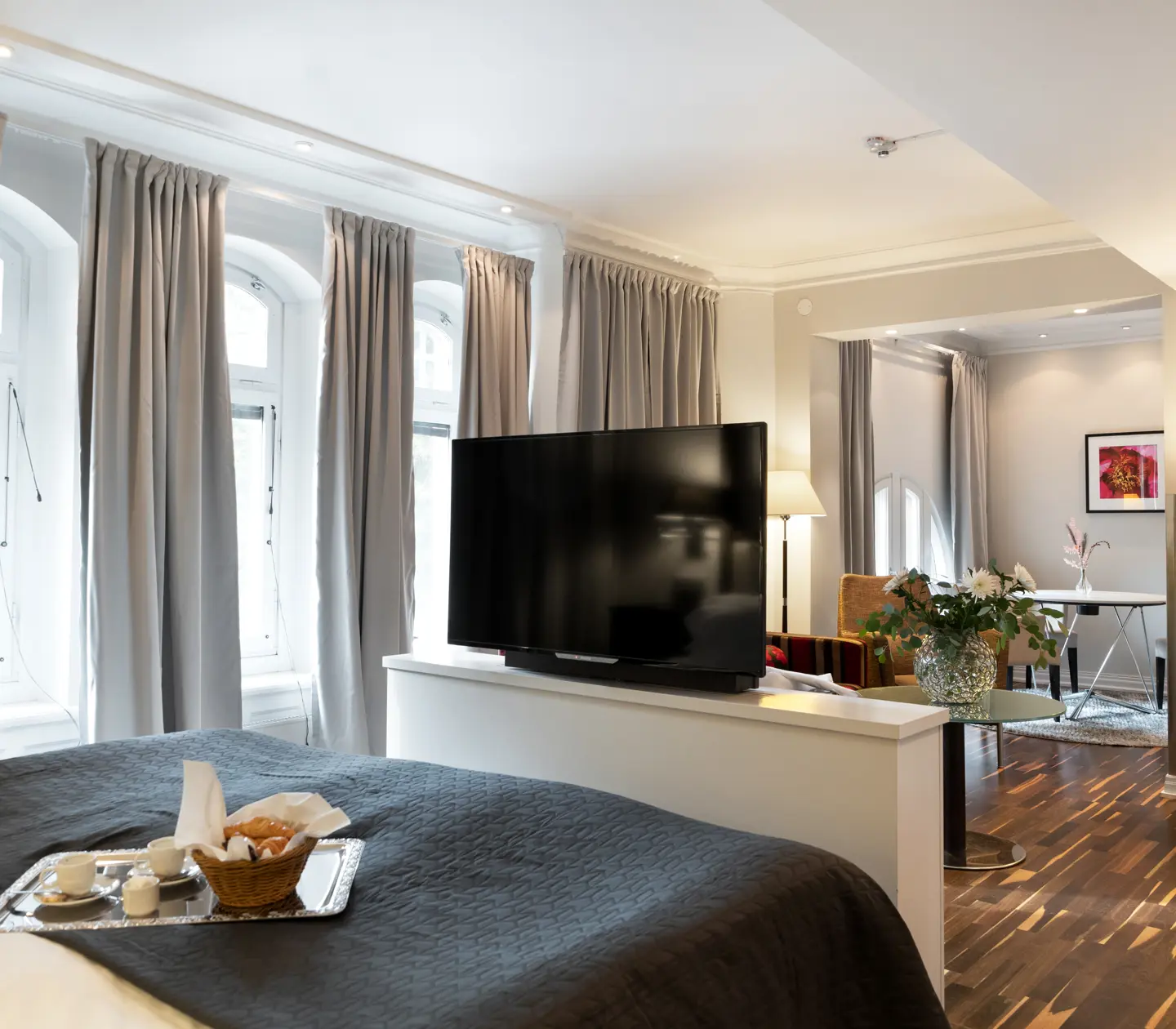 Hotellrum med många fönster, bukett och frukostbricka på säng