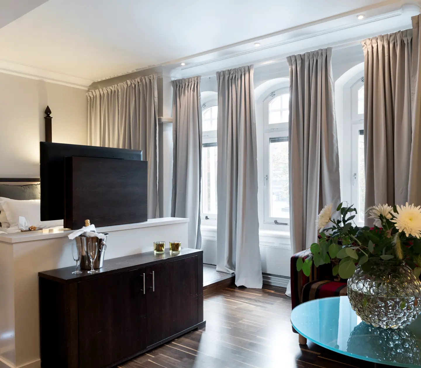 Hotellrum med säng, bukett och många fönster