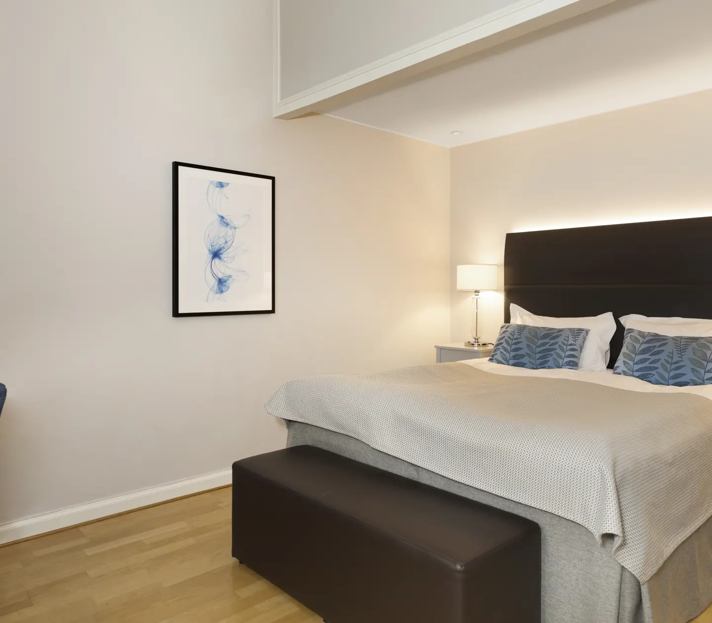 Ljust hotellrum med säng, skrivbord och tavla