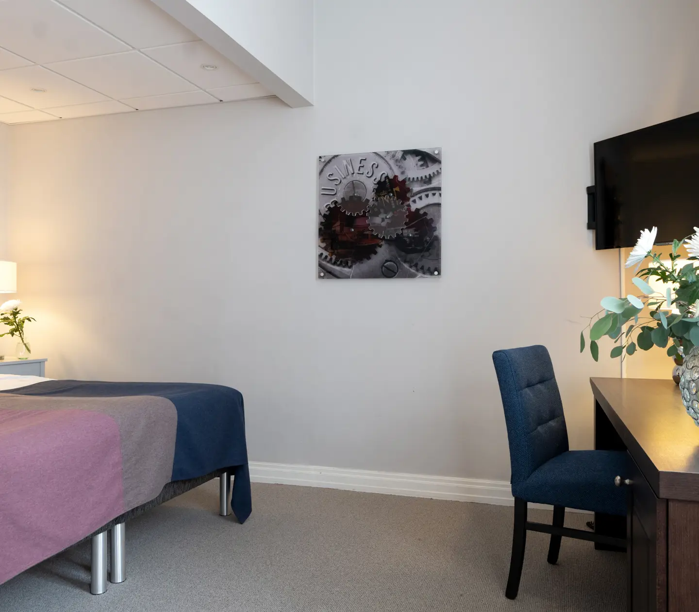 Ljust hotellrum med säng, skrivbord och tv