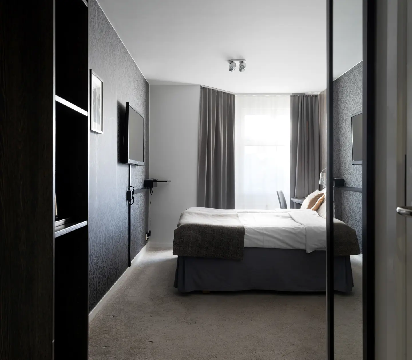 Hotellrum med dubbelsäng, fönster och tv
