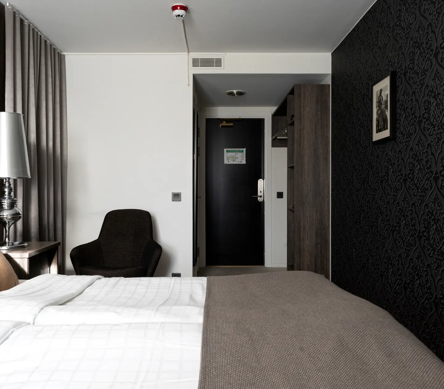 Hotellrum med dubbelsäng, fåtölj och lampa