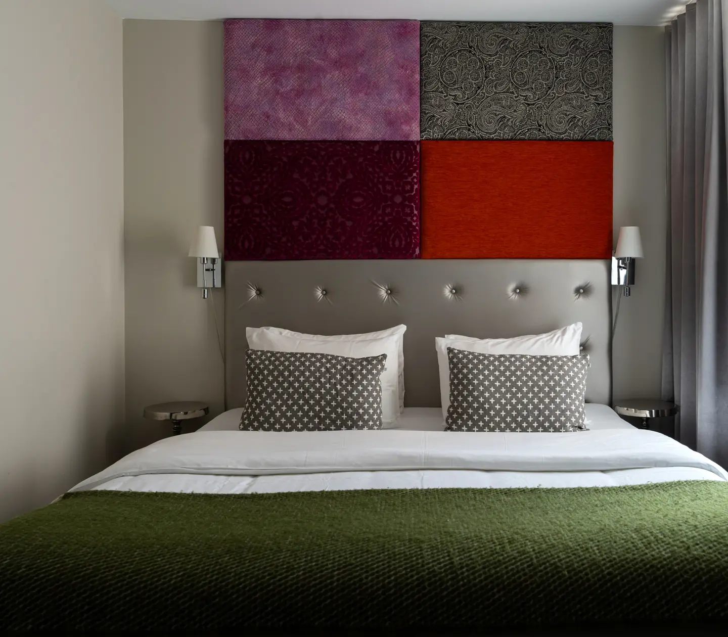Hotellrum med dubbelsäng och färgglad sänggavel
