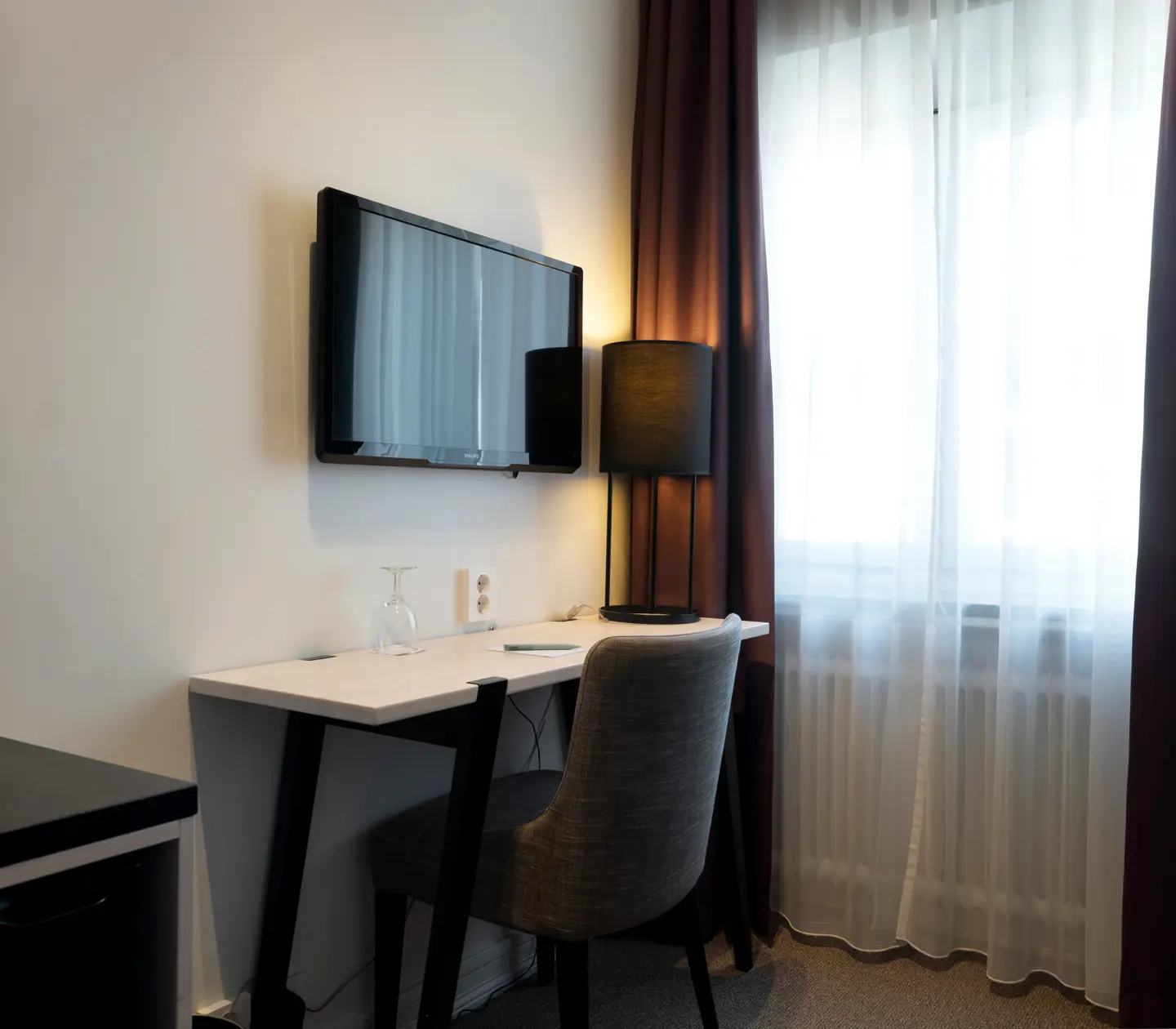 Mysigt enkelrum med tv, skrivbord och fönster