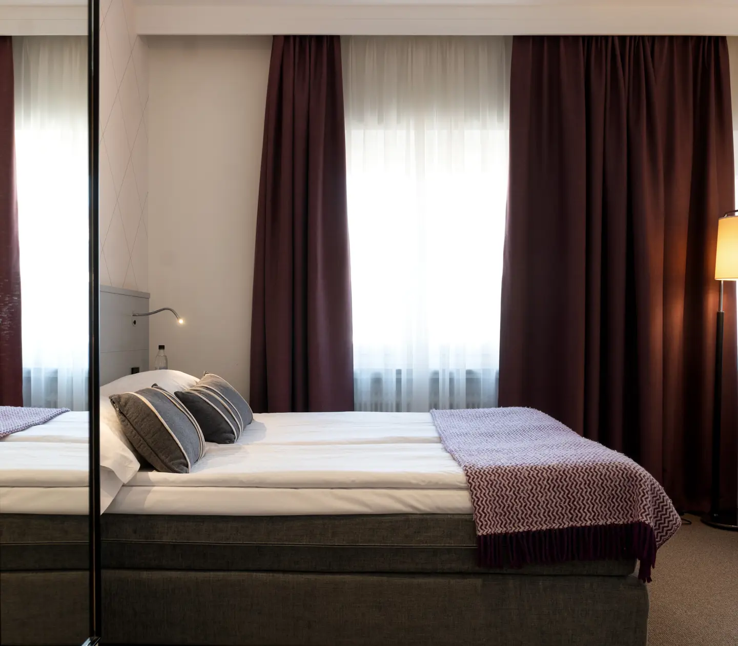 Hotellrum med dubbelsäng, fåtölj och fönster