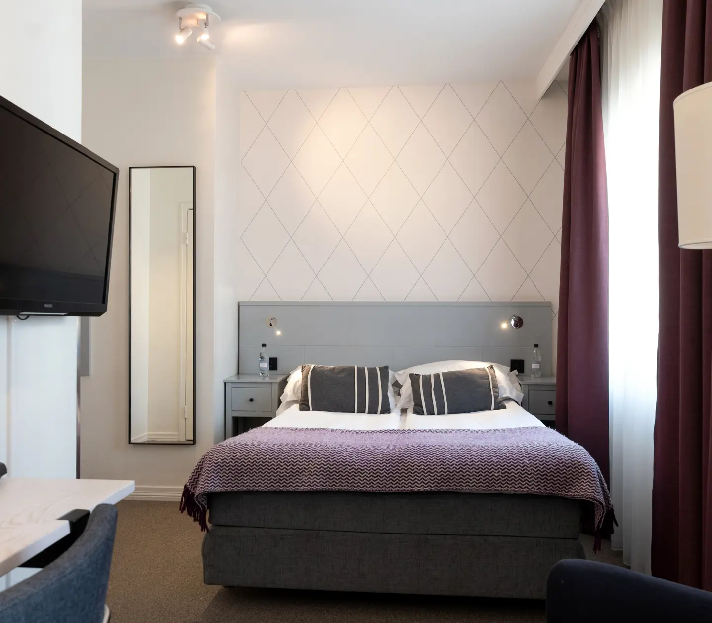 Hotellrum med dubbelsäng, tv, skrivbord och fönster