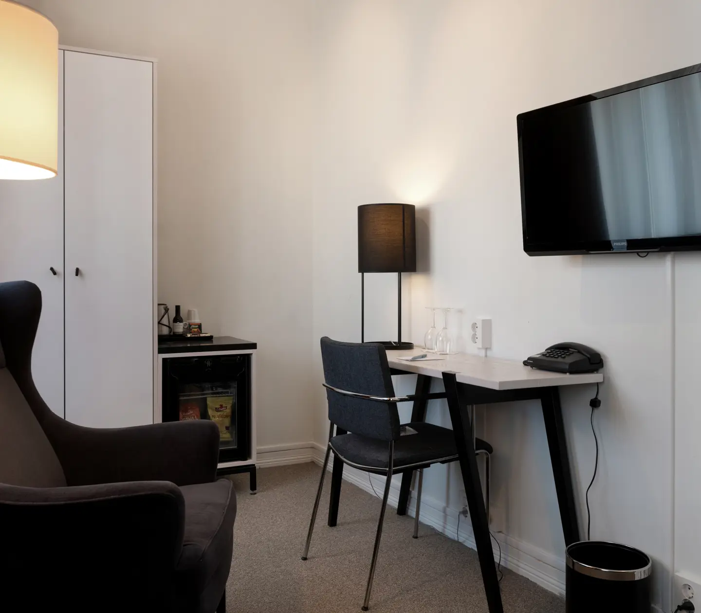 Hotellrum med skrivbord, tv, fåtölj och garderob