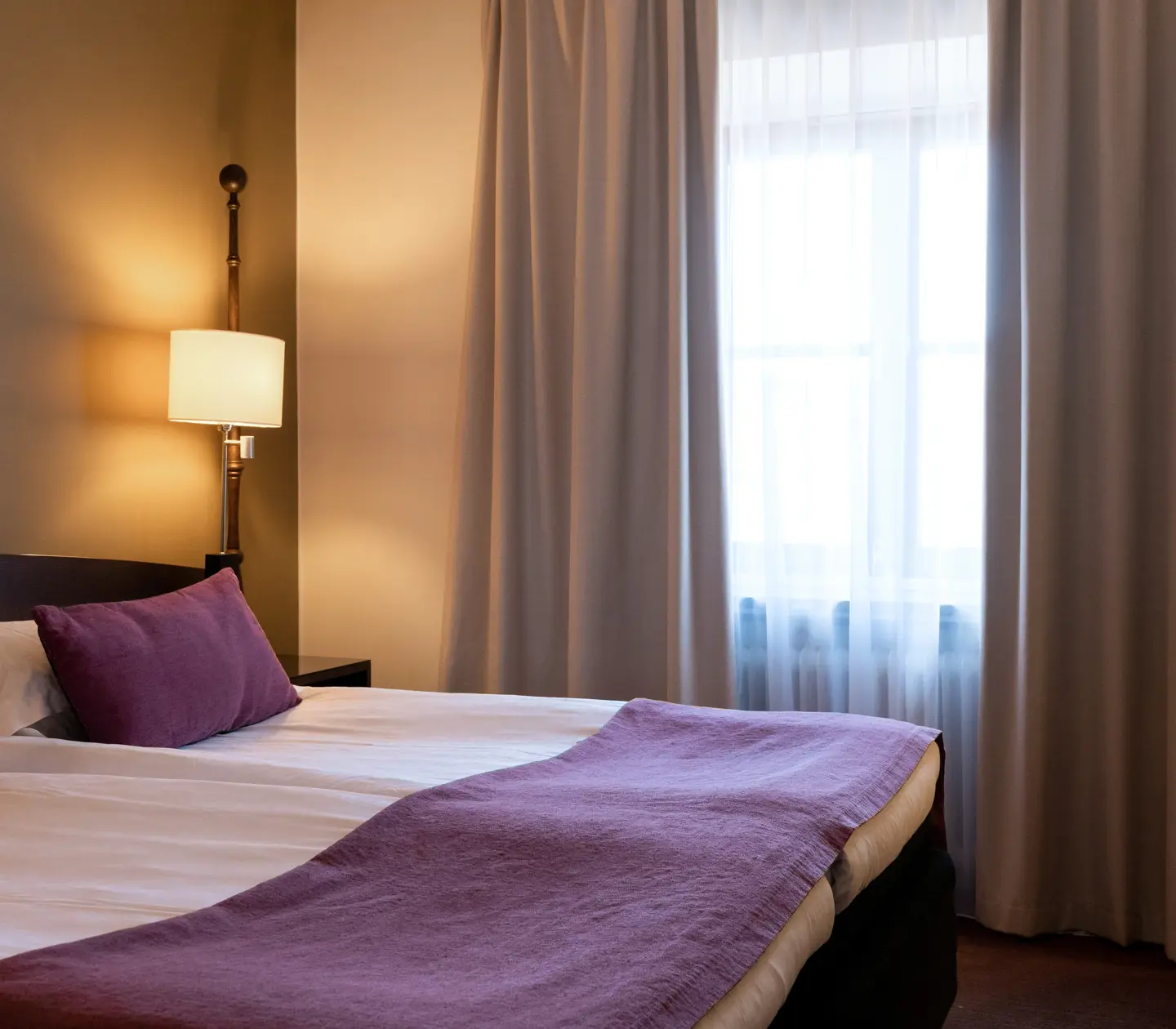 Hotellrum med dubbelsäng, fåtölj och fönster