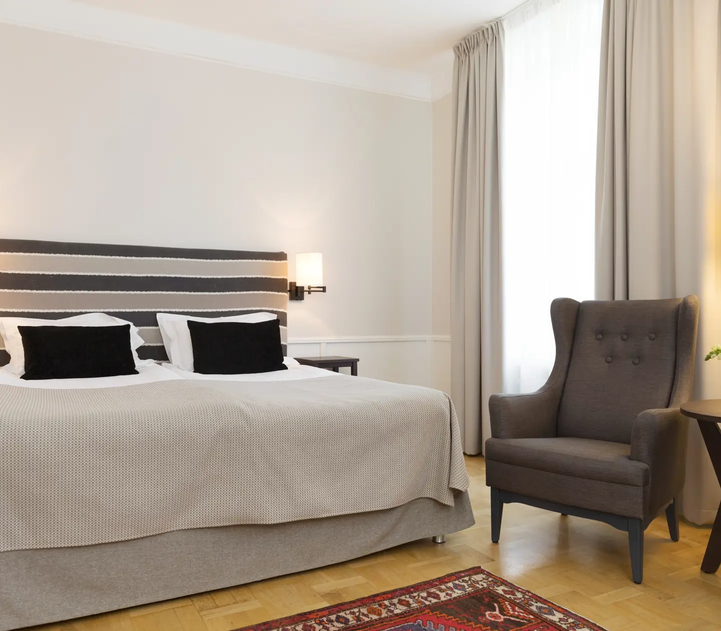 Hotellrum med dubbelsäng, fåtöljer och fönster