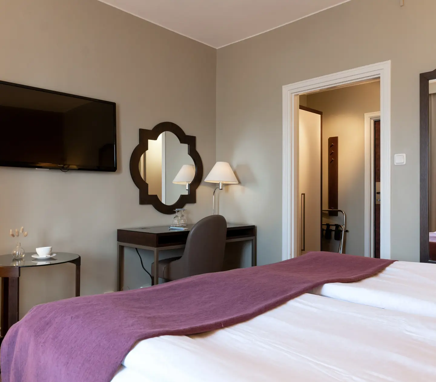 Hotellrum med dubbelsäng, spegel, skrivbord och tv