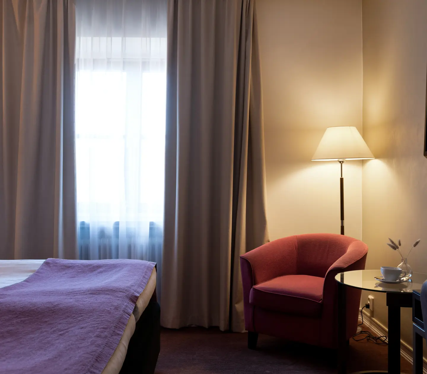 Hotellrum med dubbelsäng, fåtölj och fönster