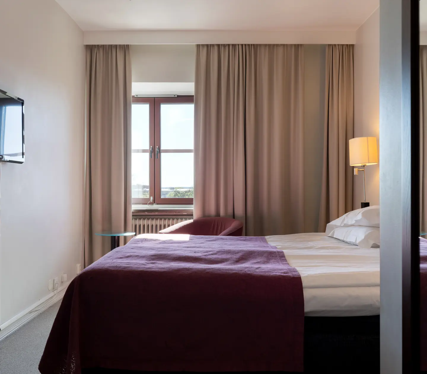 Hotellrum med dubbelsäng, fåtölj och fönster