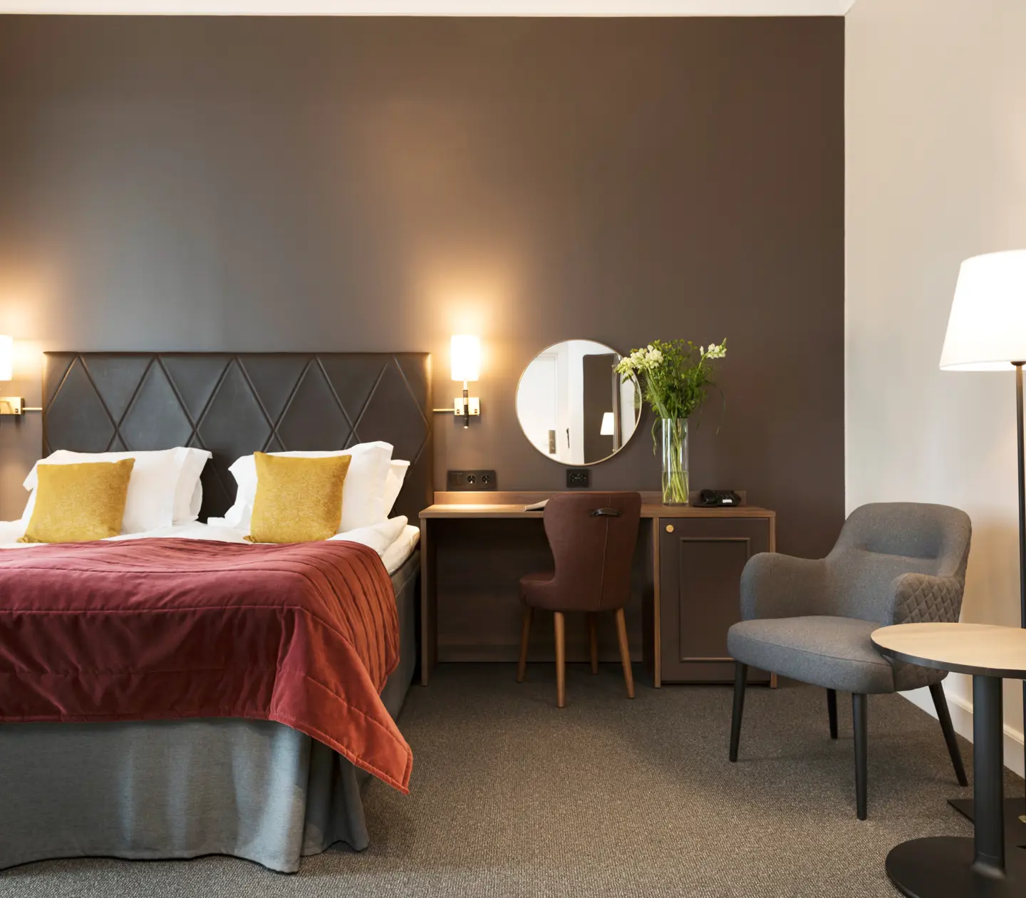 Mysigt hotellrum med dubbelsäng, skrivbord och fåtöljer