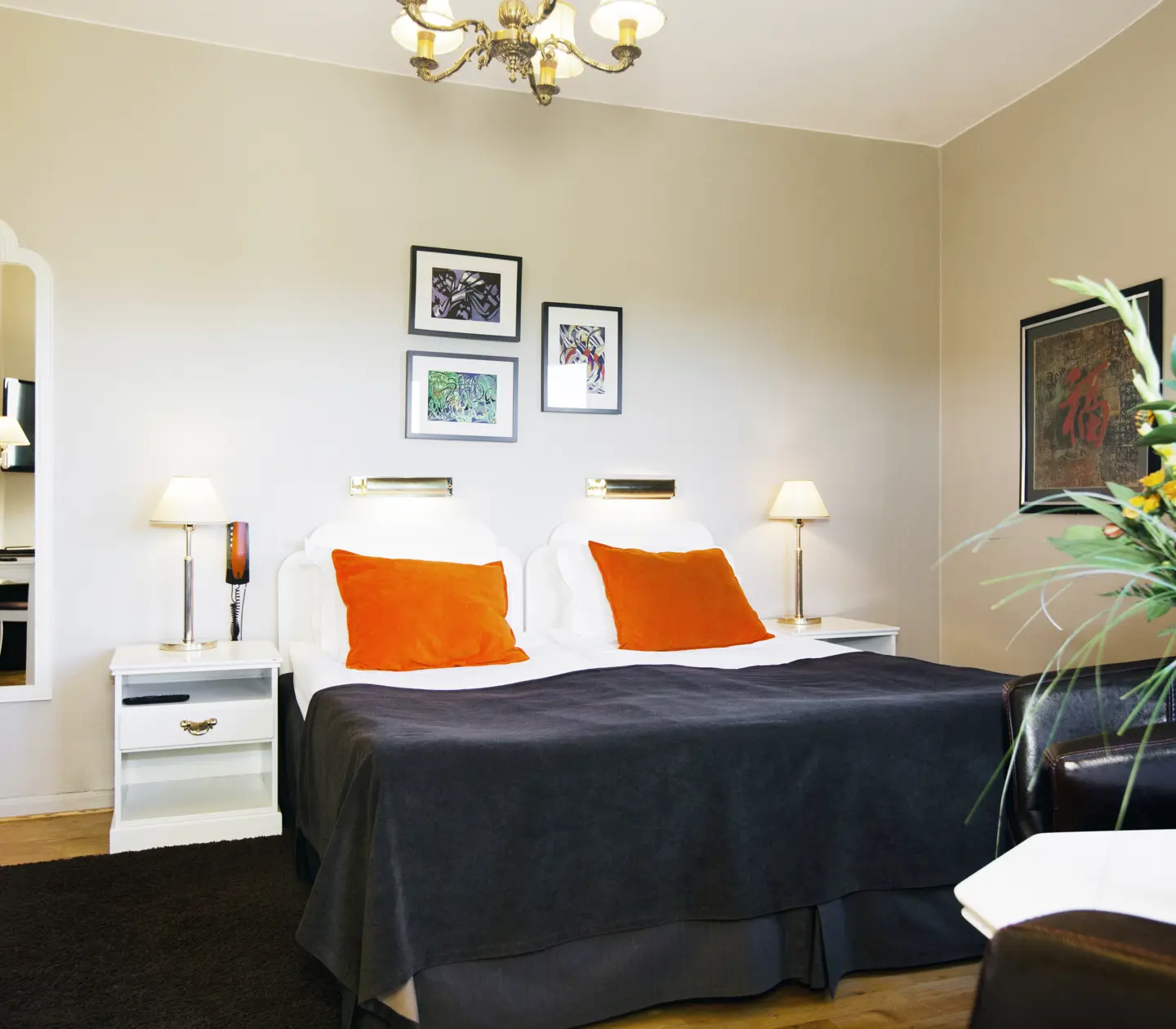 Ljust hotellrum med dubbelsäng, spegel och bukett