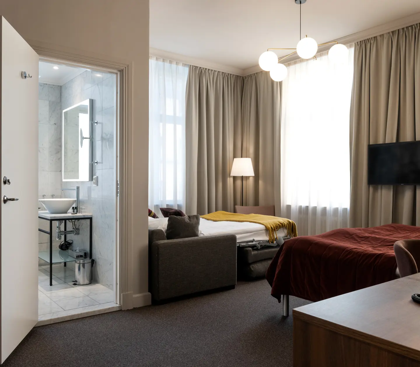 Hotellrum med dubbelsäng, bäddsoffa, badrum och skrivbord