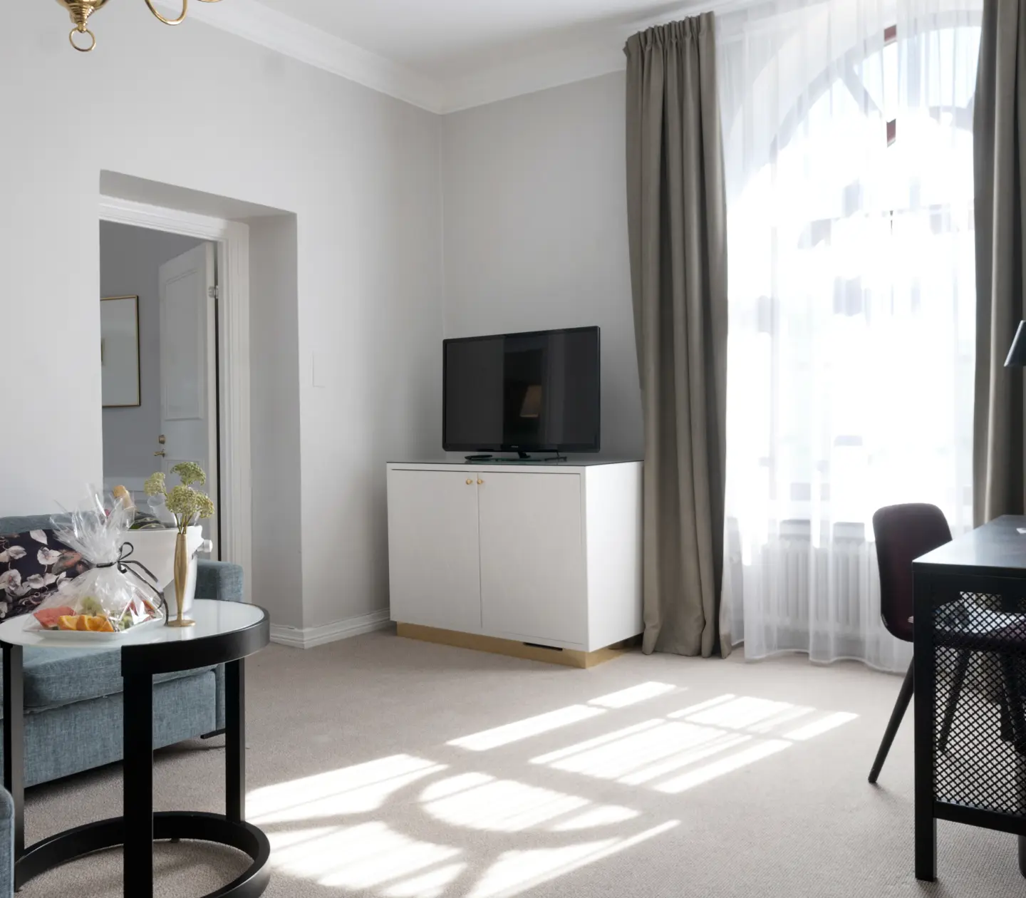 Svit med soffa, tv, skrivbord och stort fönster