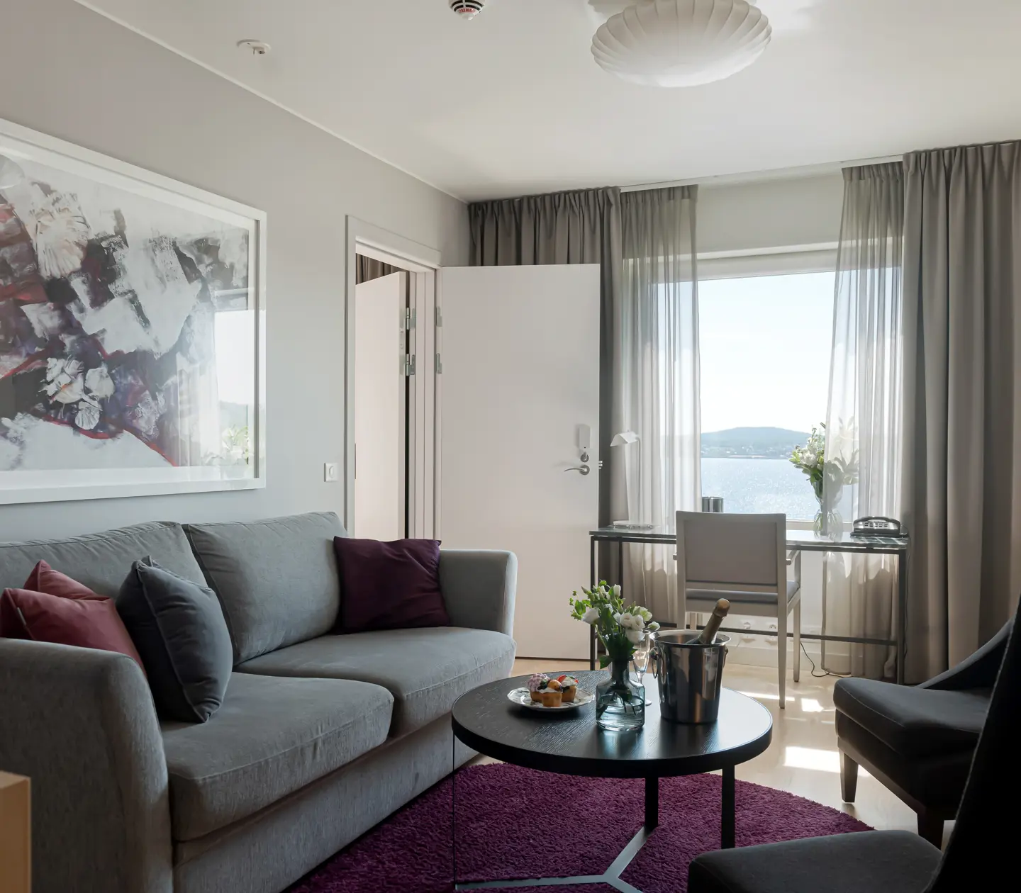 Mysig hotellsvit med soffa, fåtölj och havsutsikt