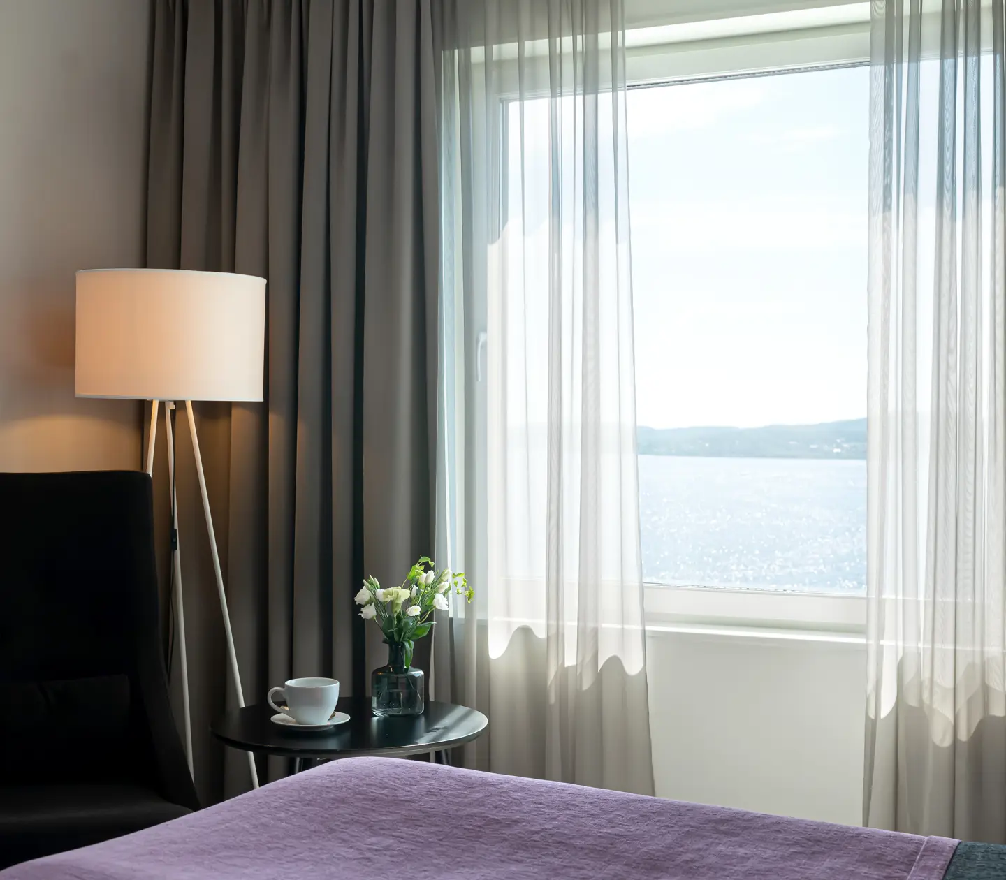 Hotellrum med säng, fåtölj och havsutsikt