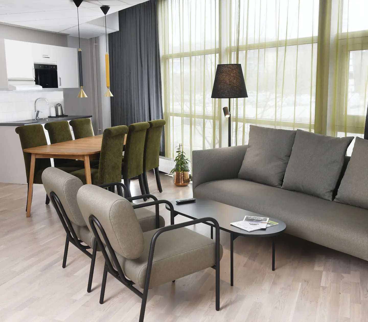 Hotellrum med soffgrupp, matgrupp, fönster och litet kök