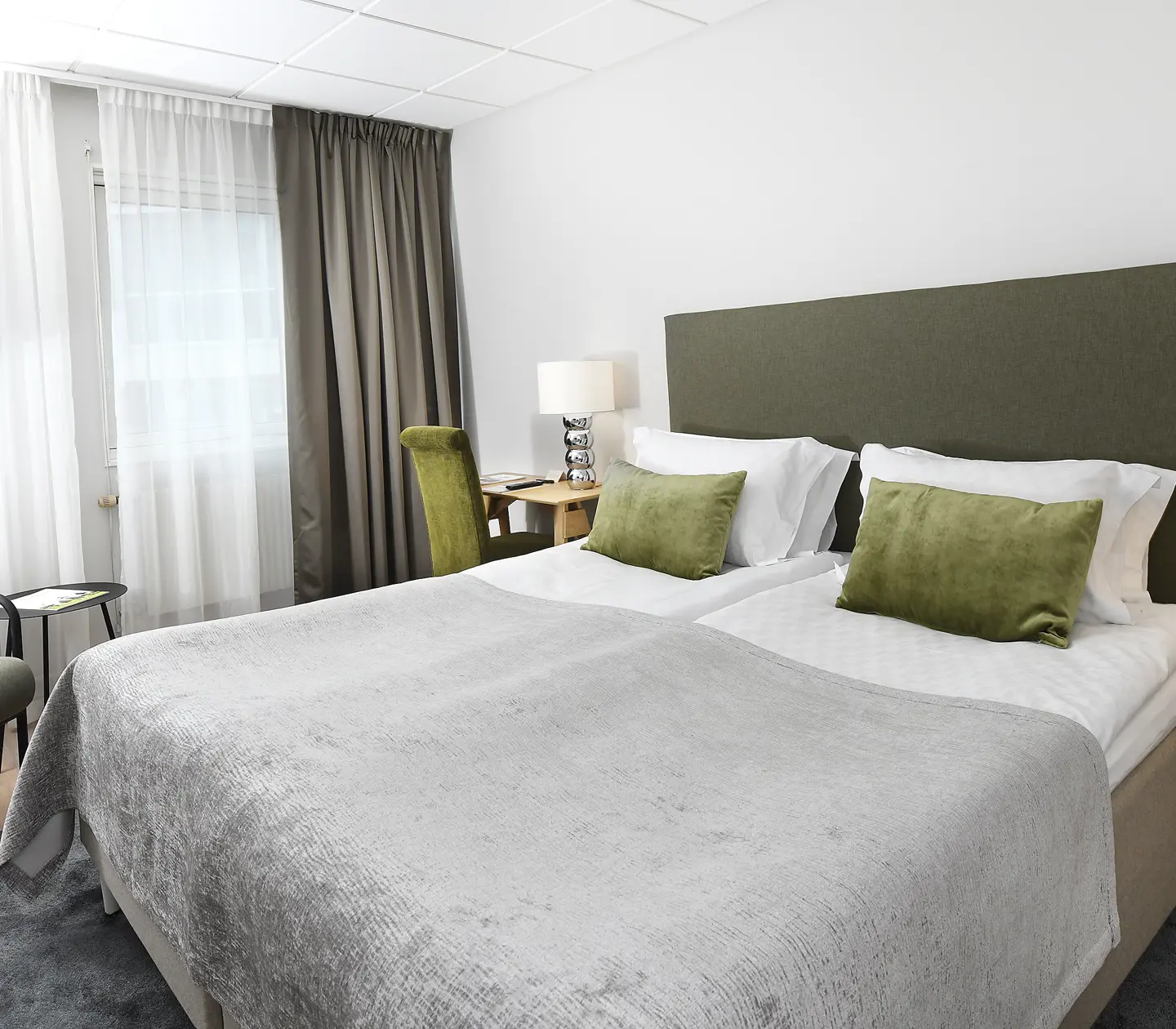 Hotellrum med dubbelsäng, skrivbord och fåtölj